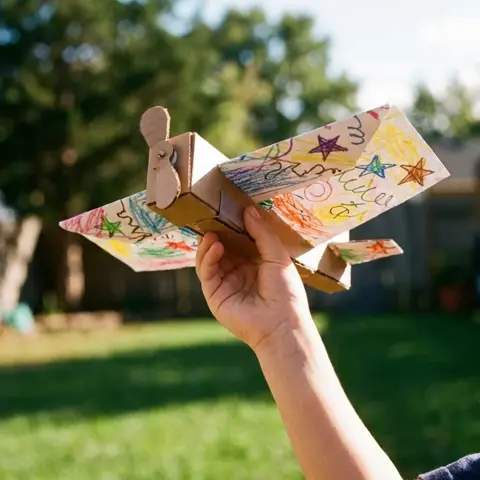 Decorated cardboard glider in a kid's hand