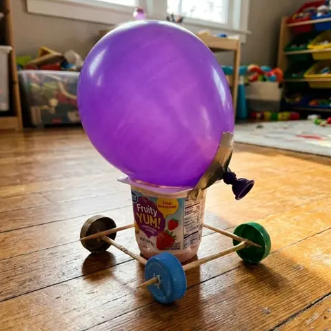 Balloon-powered car made from a yogurt cup and bottle caps